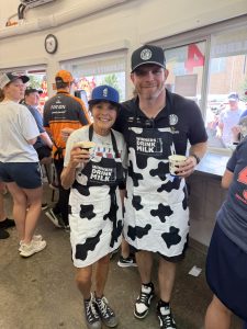 Group of men in cow‑print shorts holding cups of beverages at a storefront, smiling for the camera.